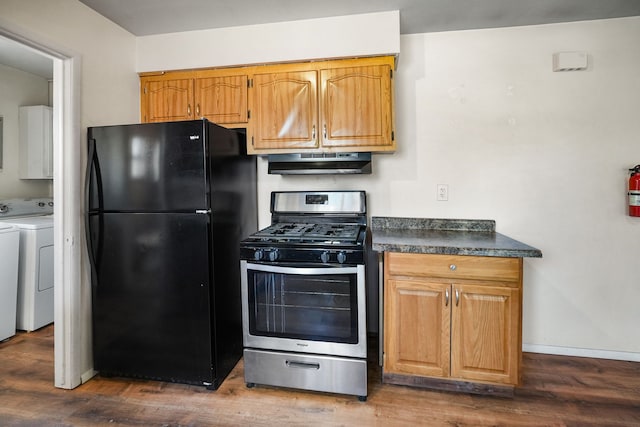 kitchen with dark wood-type flooring, under cabinet range hood, dark countertops, freestanding refrigerator, and stainless steel range with gas stovetop