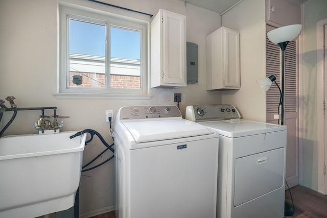 clothes washing area featuring washing machine and dryer, electric panel, wood finished floors, cabinet space, and a sink