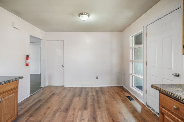 unfurnished dining area with dark wood-style floors, visible vents, and baseboards