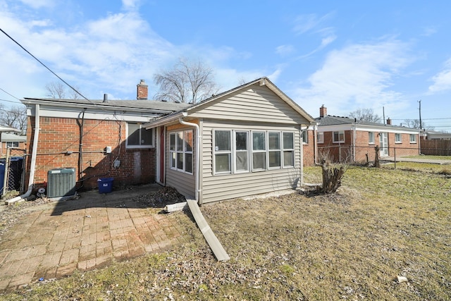 back of house featuring a patio, fence, central AC, a chimney, and brick siding