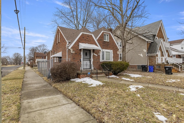 bungalow featuring a shingled roof, fence, and brick siding