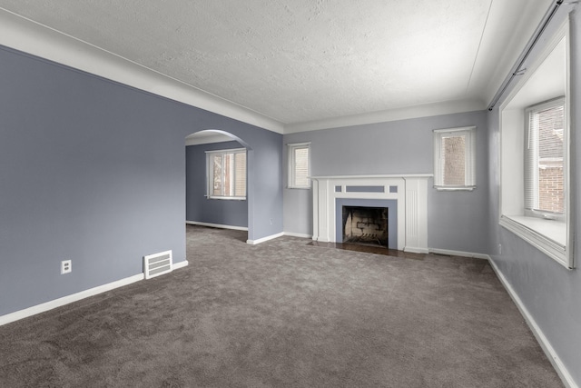 unfurnished living room with arched walkways, carpet floors, a fireplace with flush hearth, visible vents, and baseboards