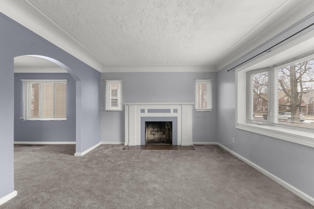 unfurnished living room featuring a fireplace with flush hearth, carpet flooring, a textured ceiling, and baseboards