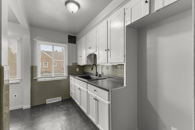 kitchen with visible vents, a sink, backsplash, and white cabinetry