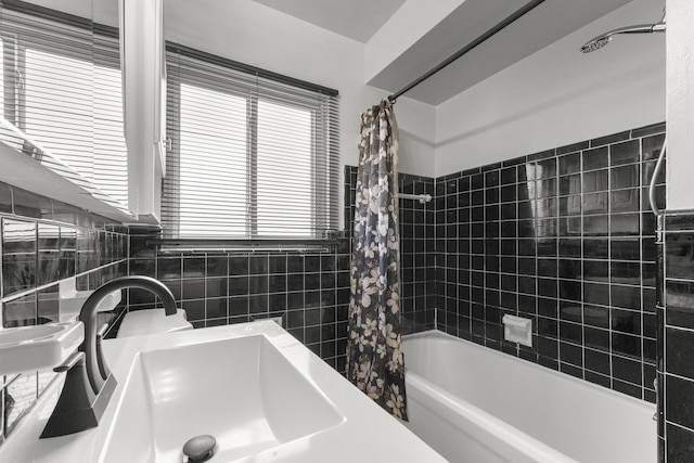 full bath with shower / tub combo, a sink, and tile walls