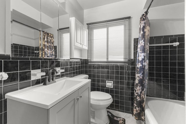 full bath featuring shower / bath combo, vanity, toilet, and tile walls