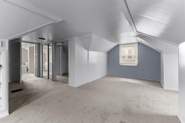 bonus room with carpet floors, visible vents, and vaulted ceiling