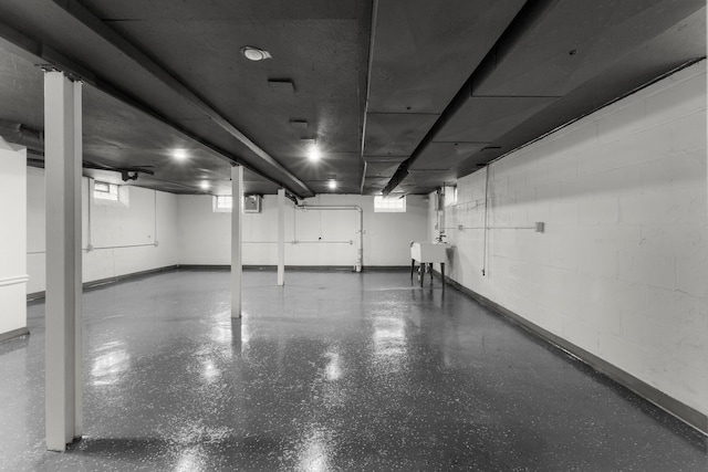 garage featuring concrete block wall, baseboards, and a sink