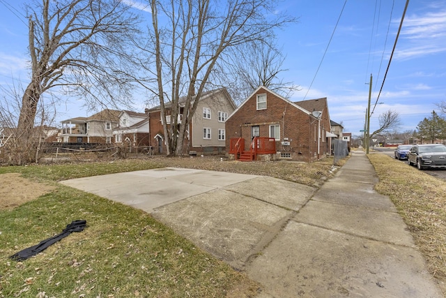 view of front of house featuring a residential view, brick siding, and fence