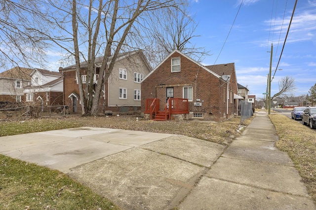 bungalow-style house with a residential view, brick siding, and fence