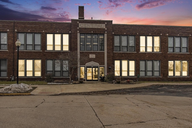 back of house at dusk with french doors and brick siding