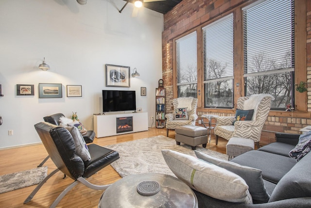 living room featuring a high ceiling, a fireplace, and wood finished floors