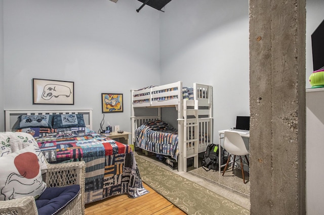 bedroom with a high ceiling and wood finished floors