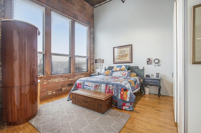 bedroom with wood-type flooring and brick wall