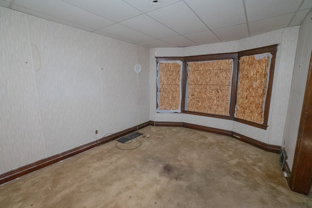 spare room featuring a paneled ceiling and baseboards