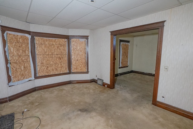 spare room with a paneled ceiling, visible vents, concrete floors, and baseboards