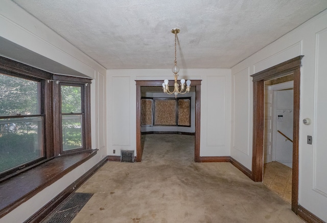 unfurnished dining area featuring visible vents, a notable chandelier, a decorative wall, and a textured ceiling