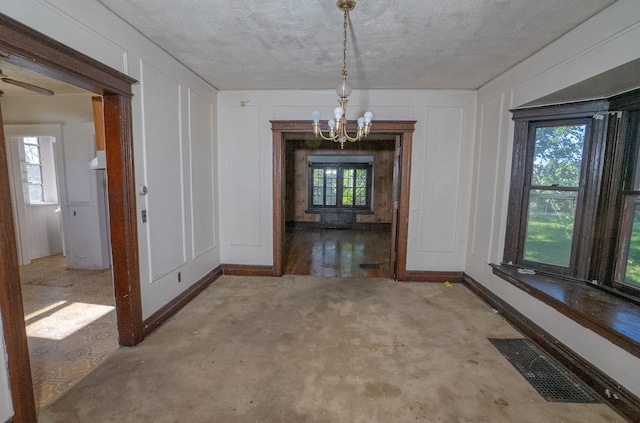 unfurnished dining area with a chandelier, baseboards, visible vents, and a decorative wall