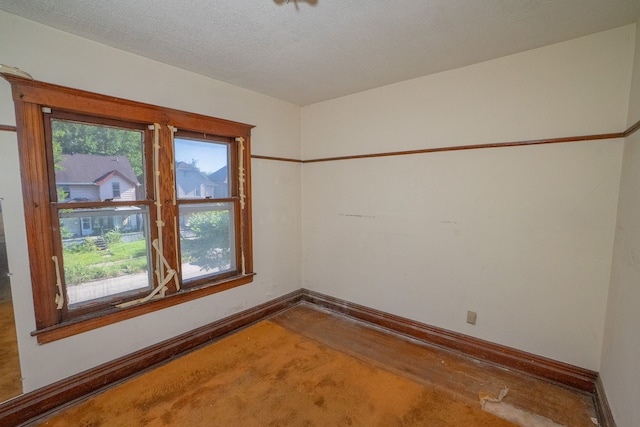 spare room with a wealth of natural light, a textured ceiling, and baseboards