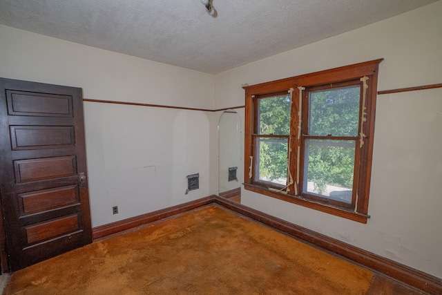 empty room featuring carpet, baseboards, and a textured ceiling