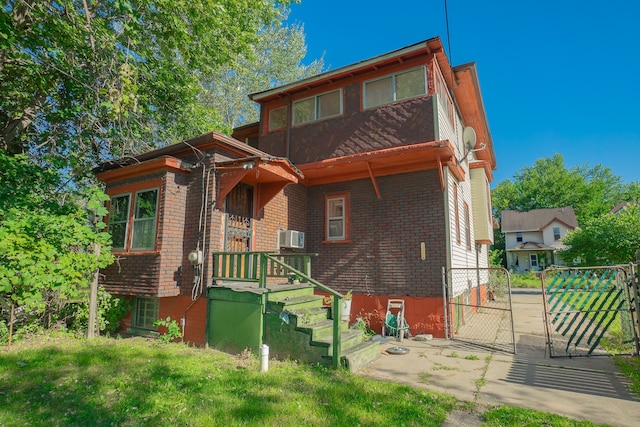 rear view of house with a gate, fence, and brick siding