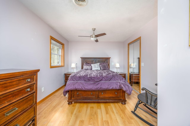 bedroom featuring light wood finished floors, baseboards, visible vents, and a ceiling fan