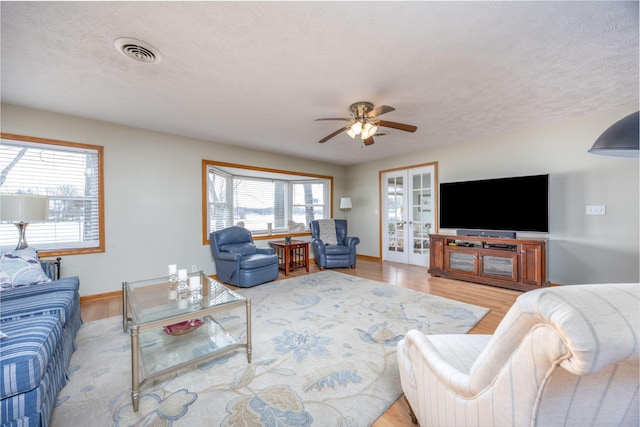 living area with light wood-type flooring, baseboards, visible vents, and a textured ceiling