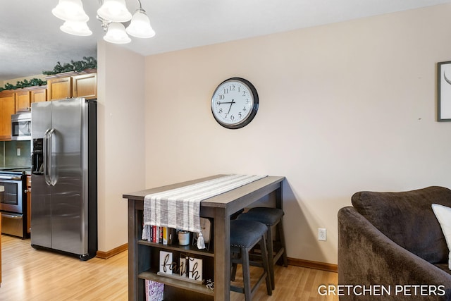 dining space featuring light wood-style flooring, baseboards, and an inviting chandelier