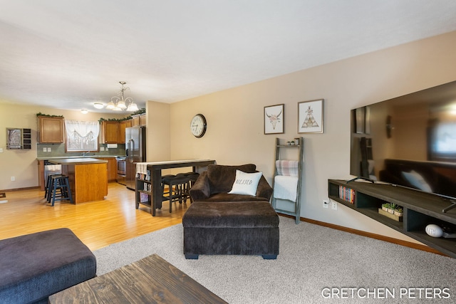 living room featuring an inviting chandelier, baseboards, and light wood-style floors