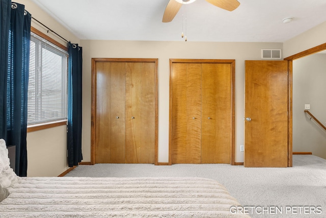 bedroom with multiple closets, visible vents, carpet flooring, ceiling fan, and baseboards