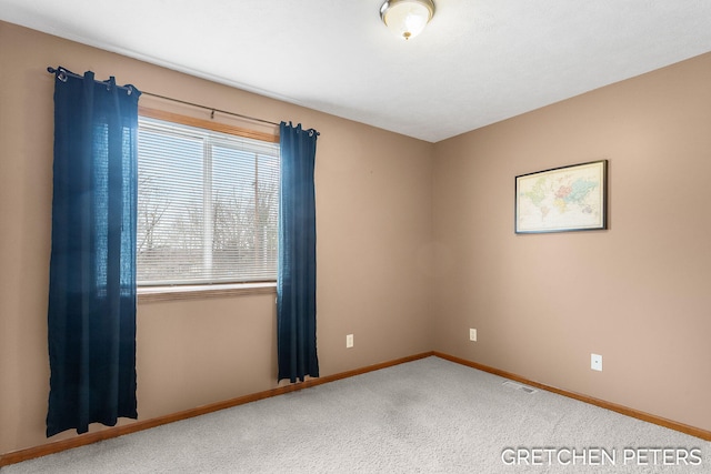 spare room featuring carpet floors, visible vents, and baseboards