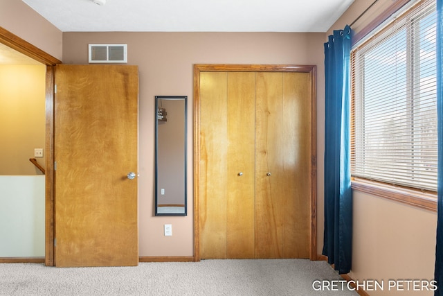 unfurnished bedroom with carpet floors, a closet, and visible vents