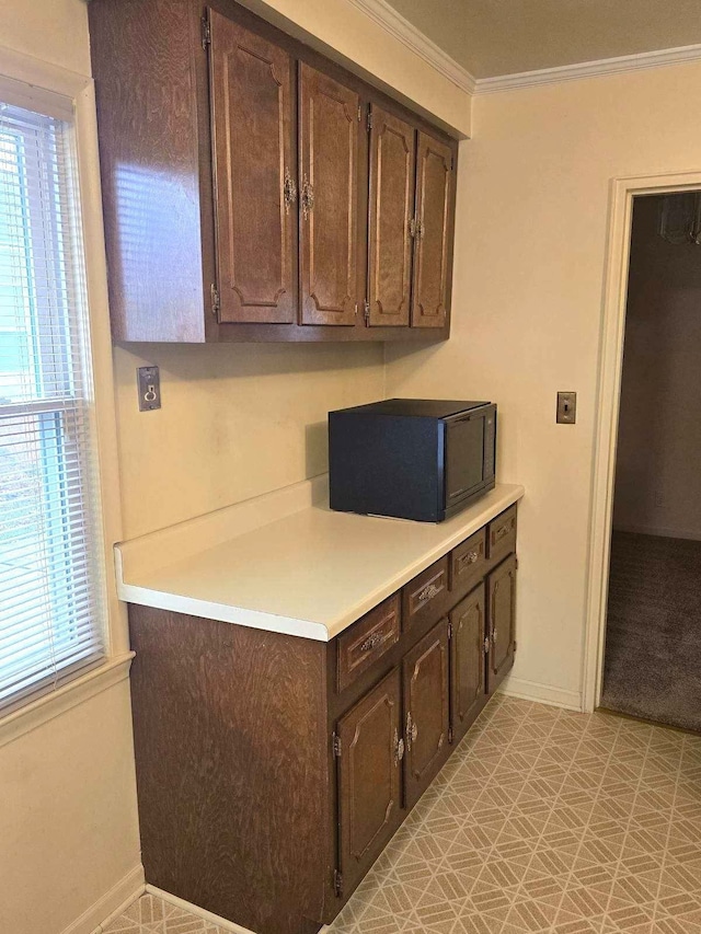 kitchen featuring dark brown cabinetry, ornamental molding, light countertops, light floors, and black microwave