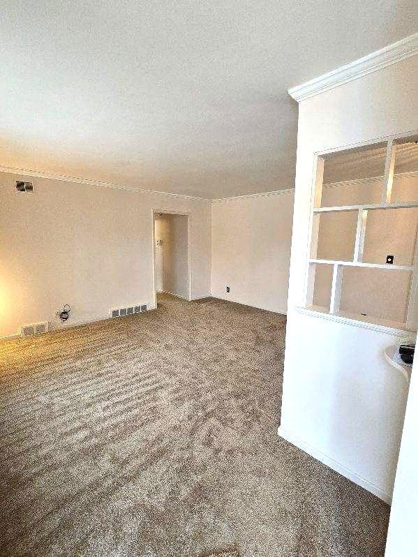 carpeted empty room with ornamental molding, visible vents, and a textured ceiling