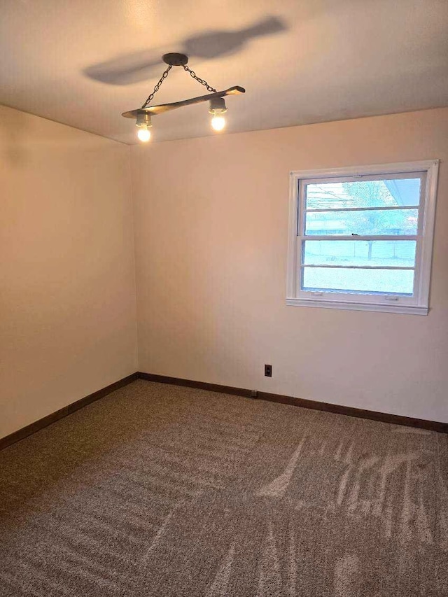 spare room featuring carpet floors and baseboards