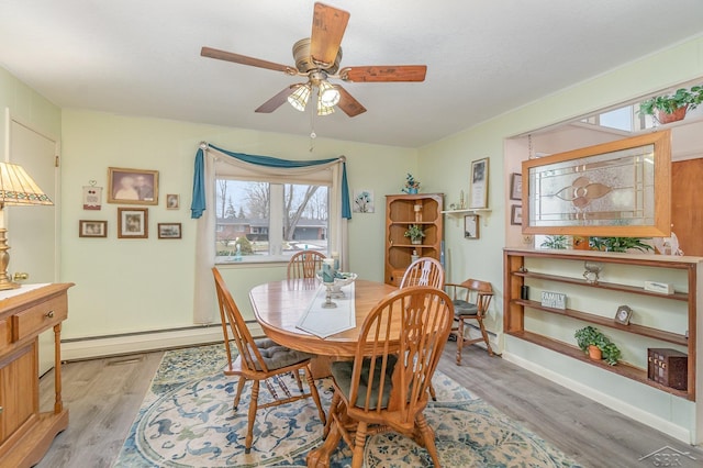 dining room with light wood-type flooring, a baseboard radiator, baseboards, and a ceiling fan