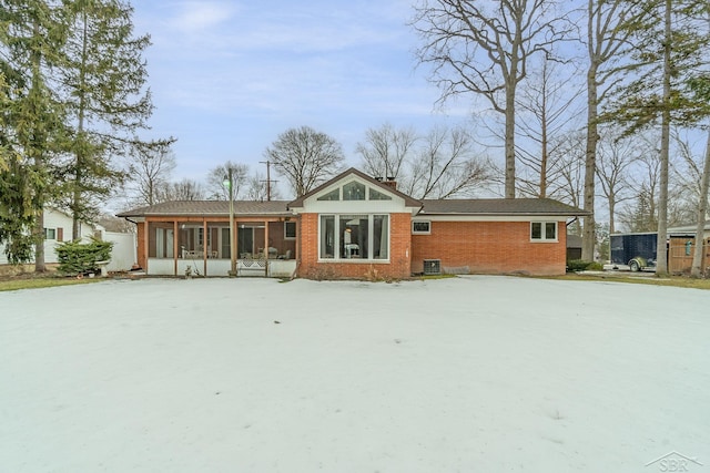 view of front facade featuring brick siding, cooling unit, and a sunroom