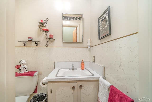 bathroom featuring toilet, a wainscoted wall, and vanity