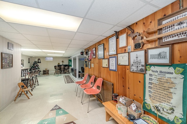 misc room with wood walls, a paneled ceiling, and tile patterned floors