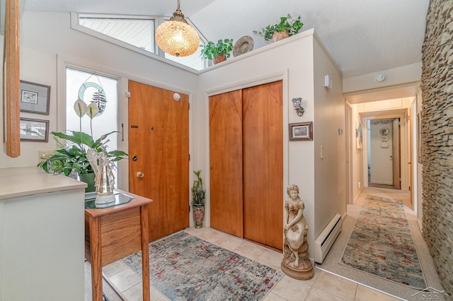 foyer entrance with a baseboard radiator, tile patterned flooring, lofted ceiling, and a textured ceiling