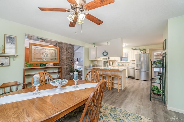 dining space with light wood finished floors and a ceiling fan