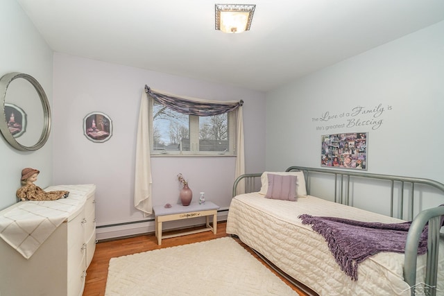 bedroom with a baseboard radiator and light wood-style flooring