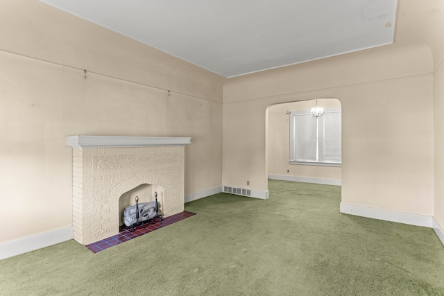 unfurnished living room with arched walkways, carpet flooring, visible vents, baseboards, and a brick fireplace