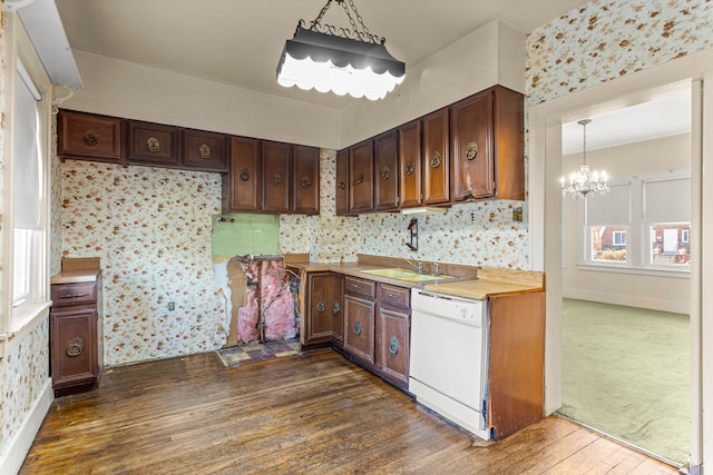 kitchen featuring dark wood-style flooring, light countertops, white dishwasher, a sink, and a chandelier