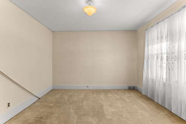 unfurnished room with baseboards, visible vents, and light colored carpet