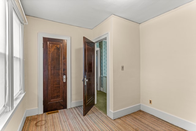 foyer with a wealth of natural light, light colored carpet, visible vents, and baseboards