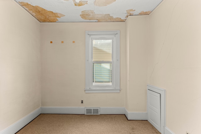 spare room featuring baseboards, visible vents, and light colored carpet