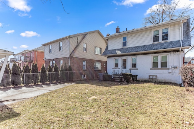 back of property featuring brick siding, a yard, a chimney, a shingled roof, and fence