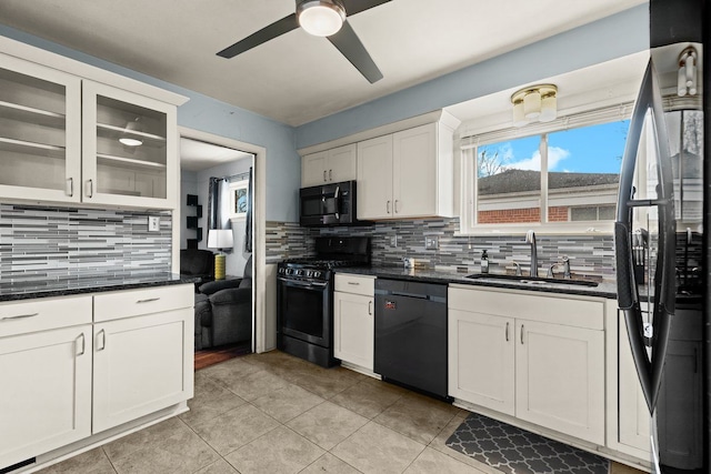 kitchen featuring black dishwasher, freestanding refrigerator, white cabinetry, a sink, and gas range