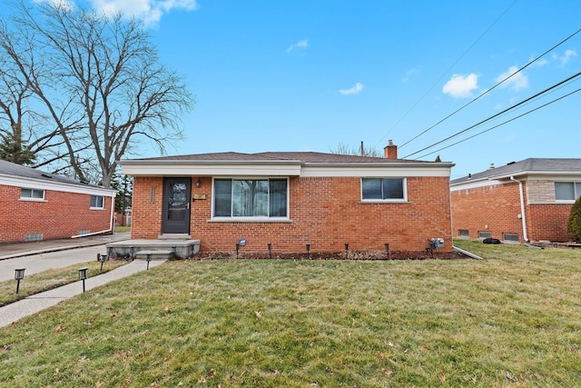 view of front of home with brick siding, a chimney, and a front yard